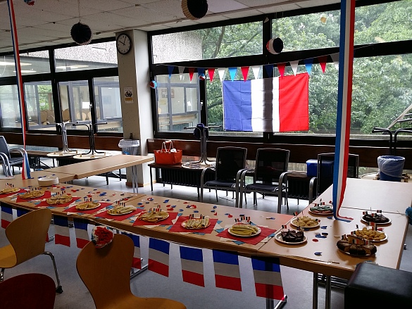 Tische und Stühle im Raum mit französischer Flagge im Hintergrund und Kuchen auf den Tischen