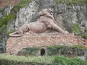 Foto einer Wandmauer mit einem eingehauenen Löwen, darüber ein Schloss oder so