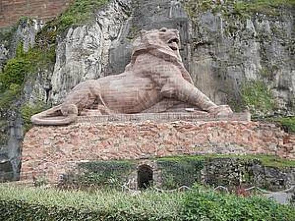 Foto einer Wandmauer mit einem eingehauenen Löwen, darüber ein Schloss oder so