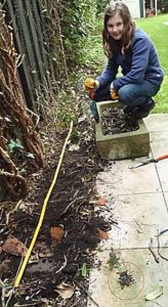 Foto einer Schülerin im Garten an einem Beet