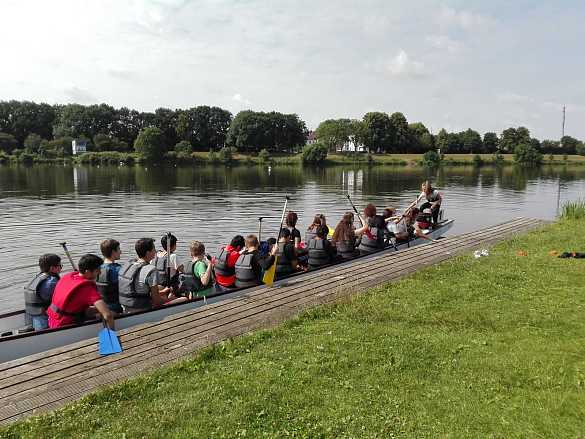 Foto von Schülern im Drachenboot an einem Anleger vom Drachenboot Cup, draußen an der Seitenweser