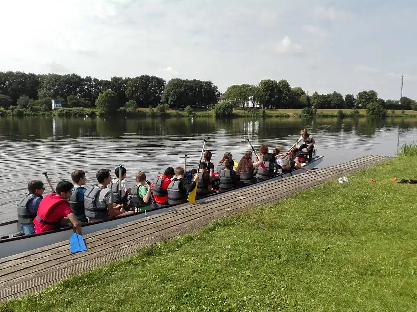 Foto von Schülern im Drachenboot an einem Anleger vom Drachenboot Cup, draußen an der Seitenweser