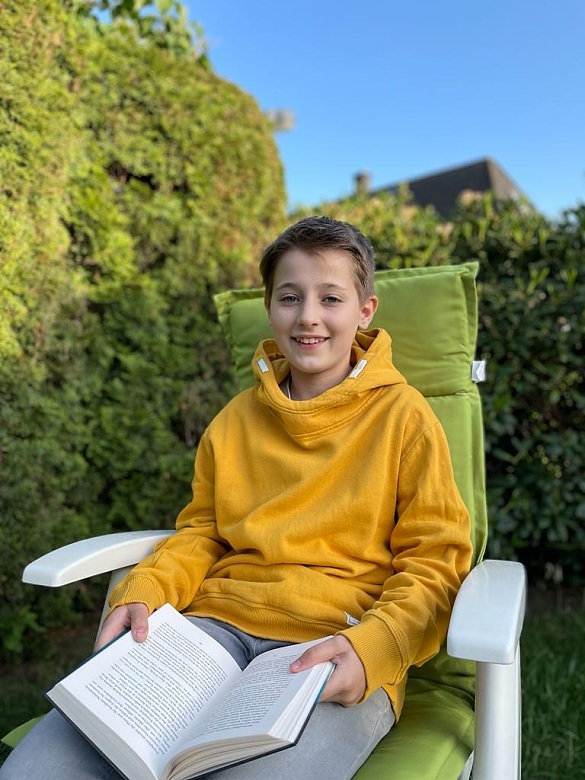 Foto des Gewinners im Gartenstuhl mit einem Buch auf dem Schoß