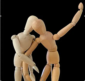 Zwei Holzfiguren die sich verschränken